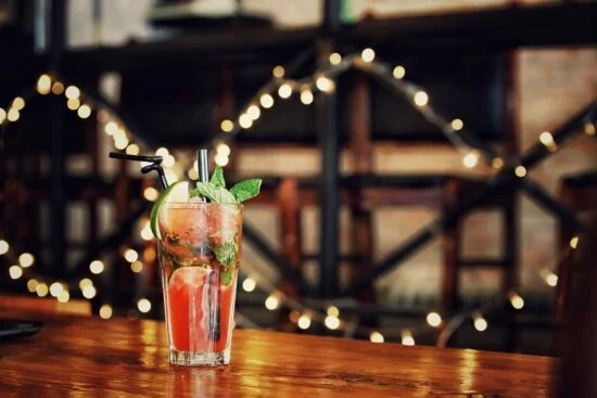 Glass of cocktail with mint on wooden table