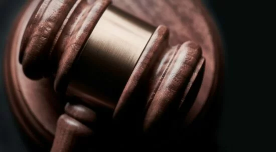 Close-up of a wooden judge’s gavel resting on a sound block.