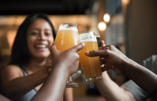 Friends clinking glasses of beer in a bar, smiling