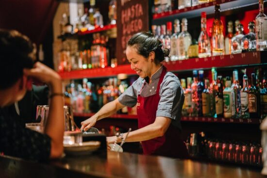 Bartender preparing a drink behind a bar counter.