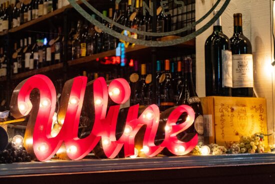 Illuminated “Wine” sign displayed in front of wine bottles