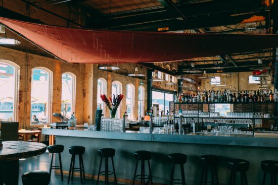 Spacious bar interior with stools, large windows, and a long counter.