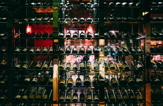 Wine bottles stored in a glass display rack.