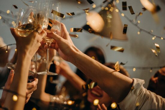 People toasting wine glasses with confetti at a celebration.