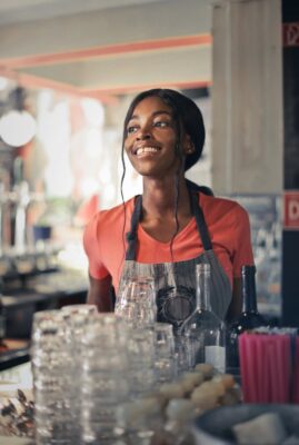 Smiling bartender standing behind a bar counter.