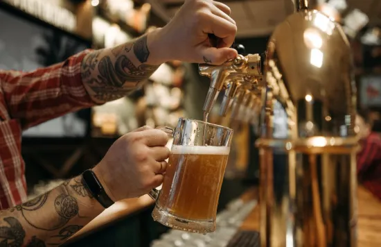 Bartender pouring beer into a mug from a tap.
