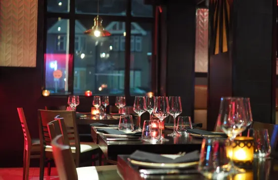 Set dining tables with wine glasses in a dimly lit restaurant.