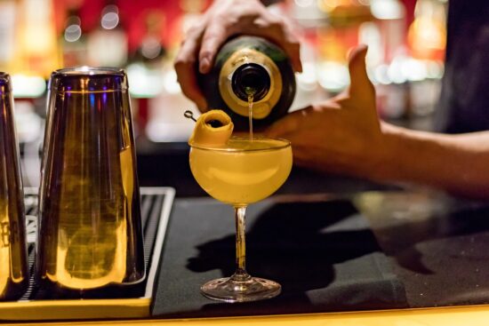 Bartender pouring a cocktail into a glass with a garnish