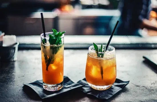 Two cocktails with mint and ice on a bar counter.