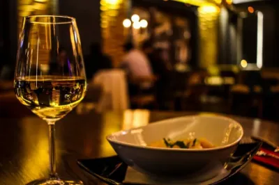 Glass of white wine and a bowl of food on a table in a restaurant.