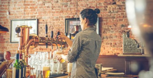 female bartender pours beer from tap