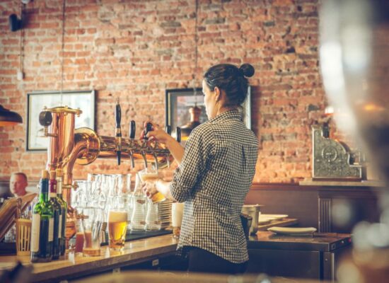 female bartender pours beer from tap