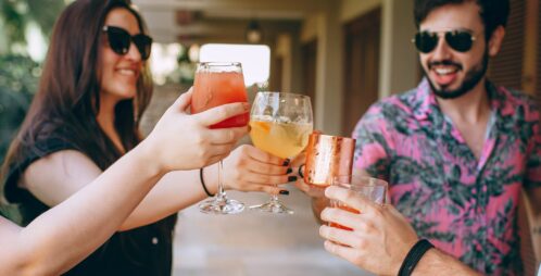 tourists wearing sunglasses toast cocktails