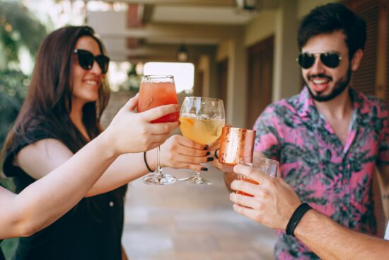 tourists wearing sunglasses toast cocktails