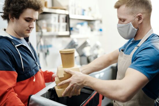 masked restaurant worker delivers boxed food