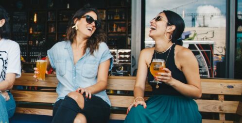 two women laughing with beer