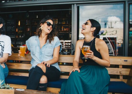 two women laughing with beer