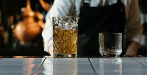 Glass of alcohol with ice at a bar