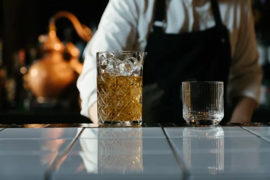 Glass of alcohol with ice at a bar